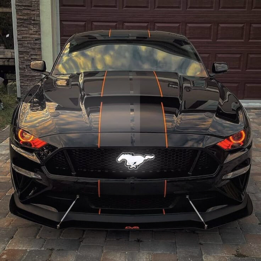 Black Mustang car with orange stripes on a driveway, and an Illuminated pony grille emblem glowing bright white