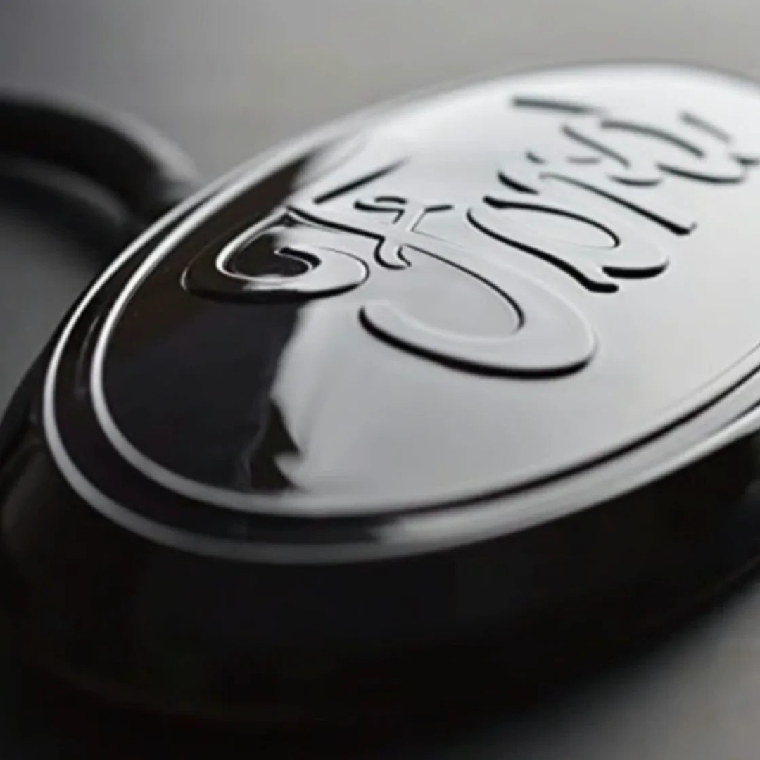 Close-up of gloss black Ford 9-inch LED grille emblem, power off, showing raised Ford script and oval detail