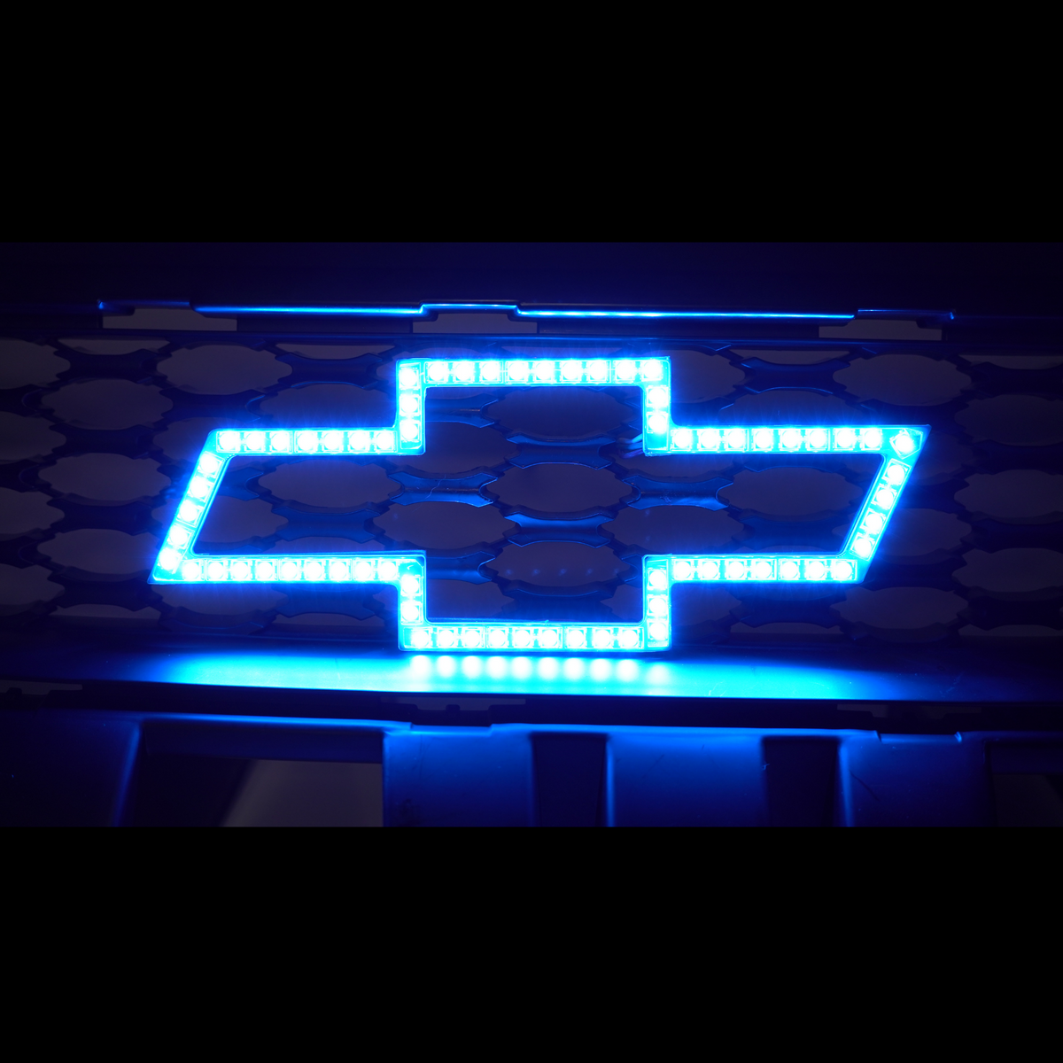 Chevrolet RGBW and Flow Series LED emblem lighting. This photo contains AutoJeweler's RGBW Illuminated Chevy logo installed on a Chevrolet front grille glowing blue.
