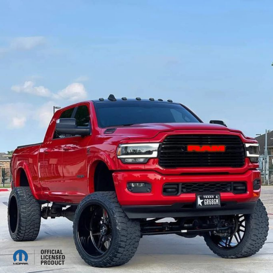 2019–2023 RAM 1500 with black RGB LED grille emblem installed, illuminated red RAM letters, on lifted red truck, Mopar Official Licensed Product