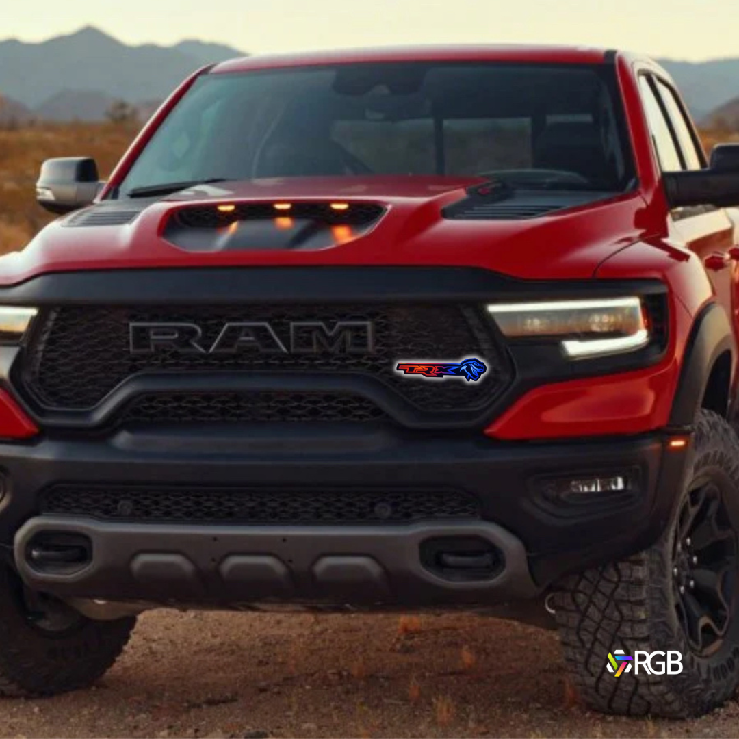 Red RAM TRX truck in a desert landscape featuring RGBW Flow Series LED grille emblem and mountains in the background.