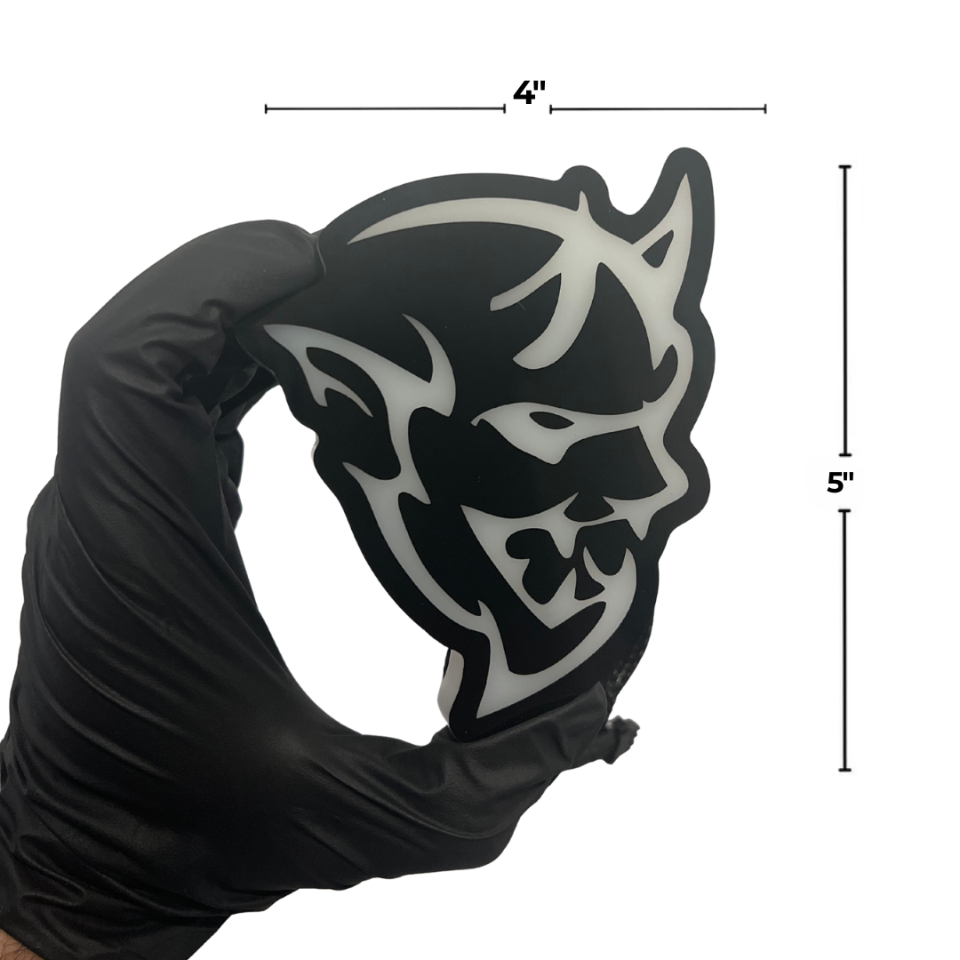 Black and white mask held by a gloved hand with measurements indicated