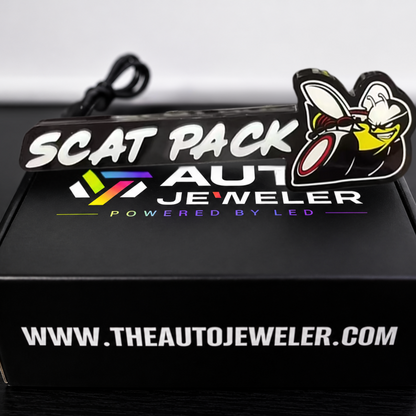 Unlit Scat Pack V2 Flow Series RGB LED Emblem displayed above black AutoJeweler branded product packaging.