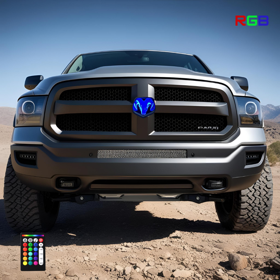 Black RAM truck with RGB illuminated grille emblem glowing blue, parked on desert terrain with clear blue sky, RGB logo and remote control visible