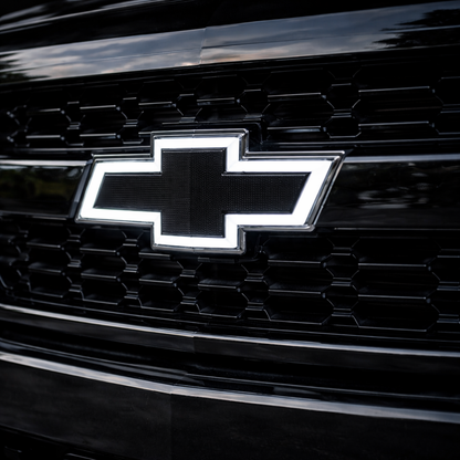 Close-up of an all black LED Chevy bowtie grille emblem with white illumination installed on a 2016–2018 Chevrolet Silverado 1500