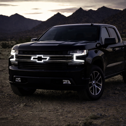 LED lighted chrome bowtie grille emblem installed on 2016–2018 Chevy Silverado 1500 with white illumination at night