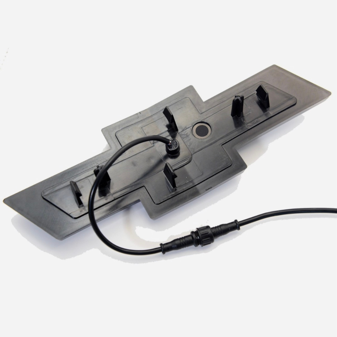 Rear view of the emblem showing mounting clips and wiring harness