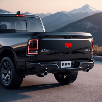 Black Ram truck with mountainous landscape in the background and a dual intensity led RAM tailgate emblem illuminated bright red.
