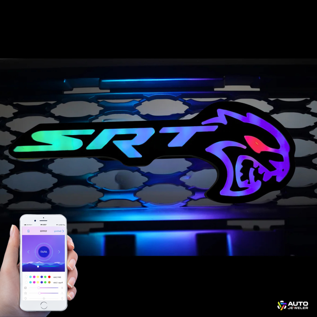 AutoJeweler Flow Series RGB LED Hellcat Redeye-style grille emblem with Bluetooth app control shown on smartphone