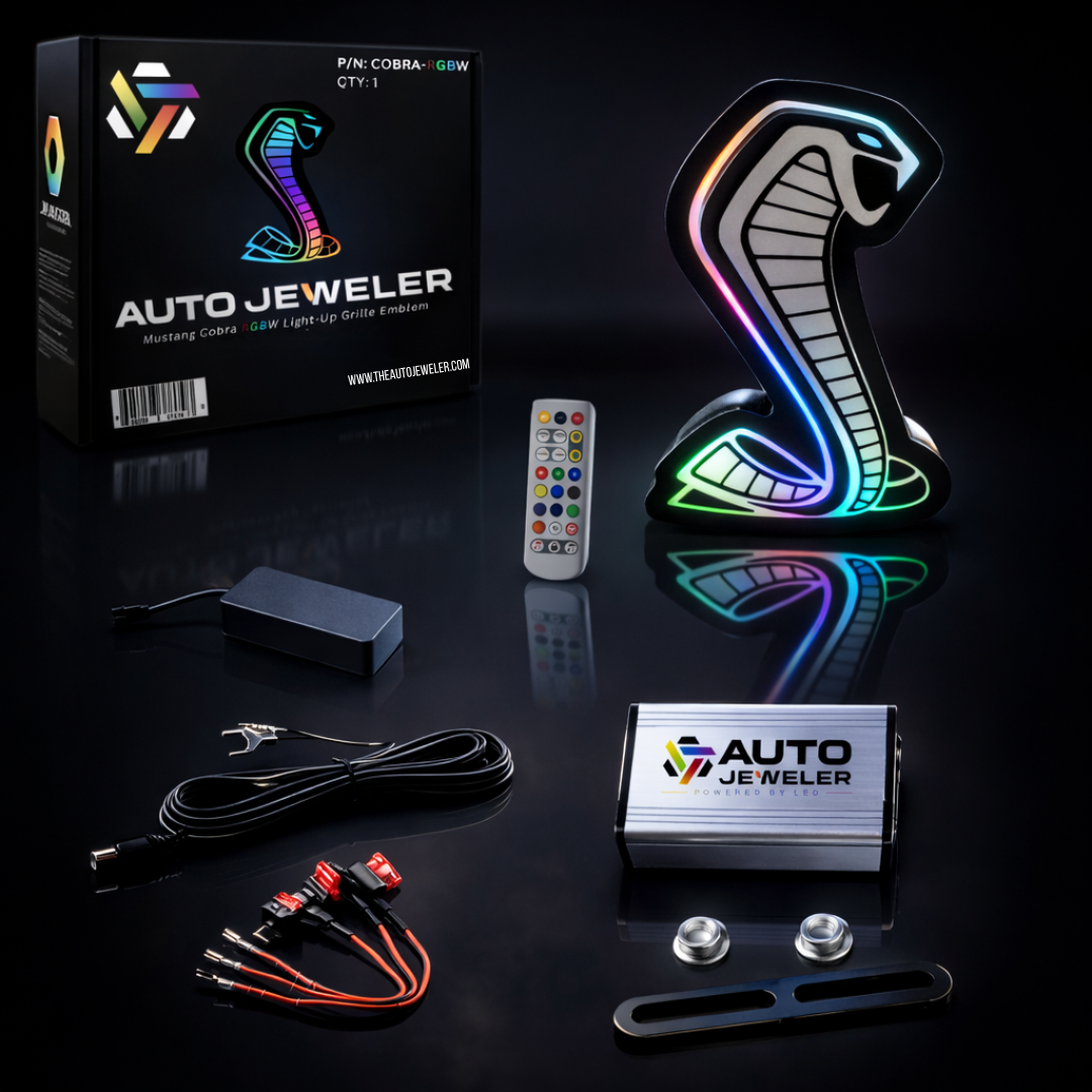 AutoJeweler Mustang Cobra RGBW LED light-up grille emblem kit with Bluetooth controller, remote, wiring harness, fuse taps, and mounting hardware