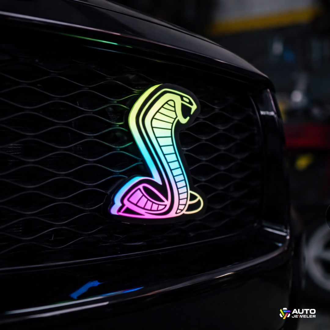 AutoJeweler Flow Series RGBW Cobra LED light-up grille emblem close-up installed on Ford Mustang grille with rainbow flow lighting