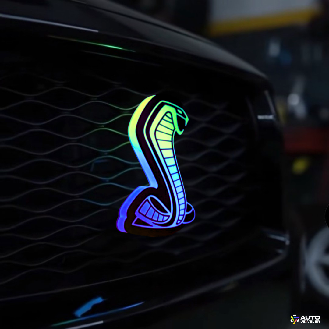 AutoJeweler Flow Series RGBW Cobra LED light-up grille emblem installed on Ford Mustang grille showing rainbow flow lighting effect