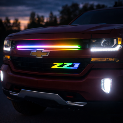 Chevy Silverado front grille with Z71 RGB Flow Series LED grille badge installed and flowing multicolor lighting at dusk