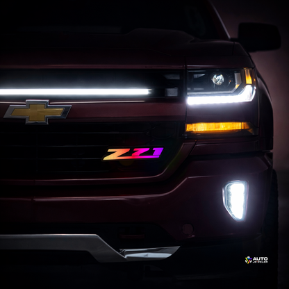 Chevy Silverado front grille at night with Z71 RGB Flow Series LED grille badge installed and flowing multicolor lighting