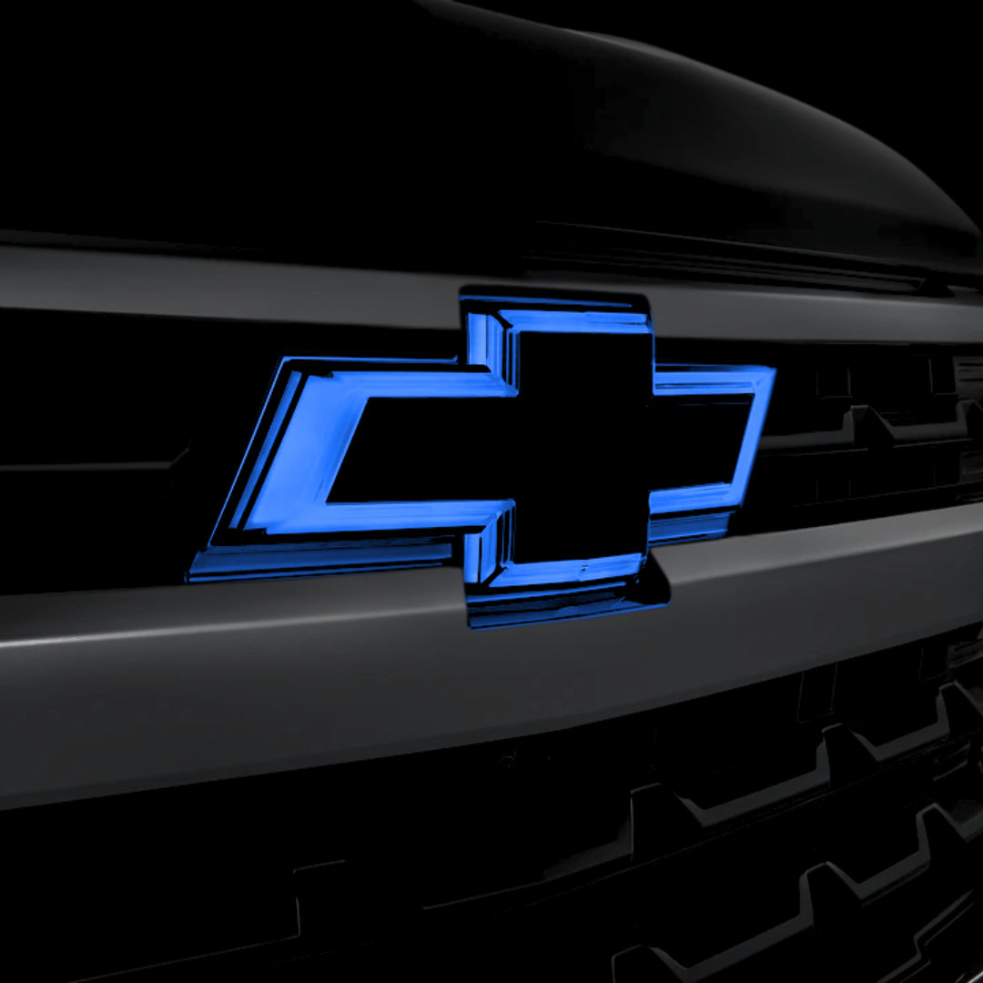 Blue-lit chrome-outline RGB LED bowtie grille emblem installed on a 2014–2015 Silverado 1500 / 2016–2019 2500HD–3500HD