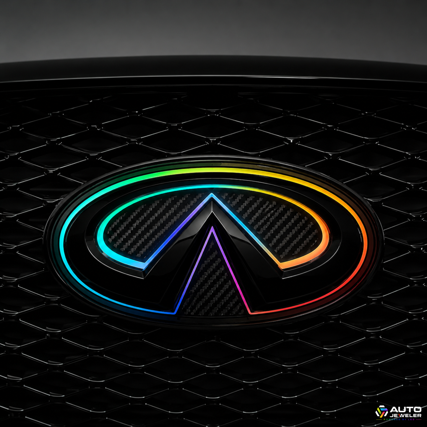 Close-up of the AutoJeweler 2018–2024 Infiniti Q50 V2 Multicolor Flow Series LED grille emblem featuring a gloss black housing, carbon fiber face, and animated RGB Flow lighting installed in the factory grille.