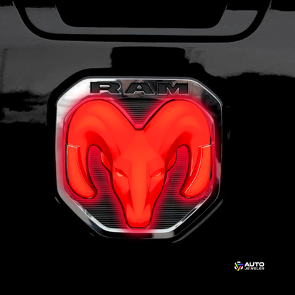 Close-up of the red LED RAM tailgate emblem lit up on the truck’s tailgate with AutoJeweler branding in the corner.
