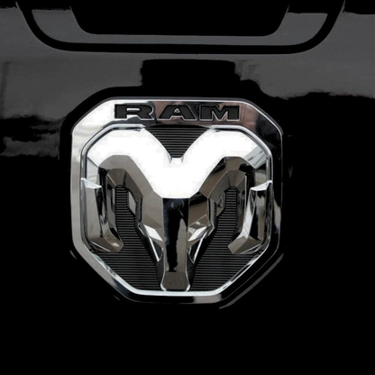 Close front view of the OEM-style chrome and black RAM tailgate emblem installed on a black truck with LEDs turned off.