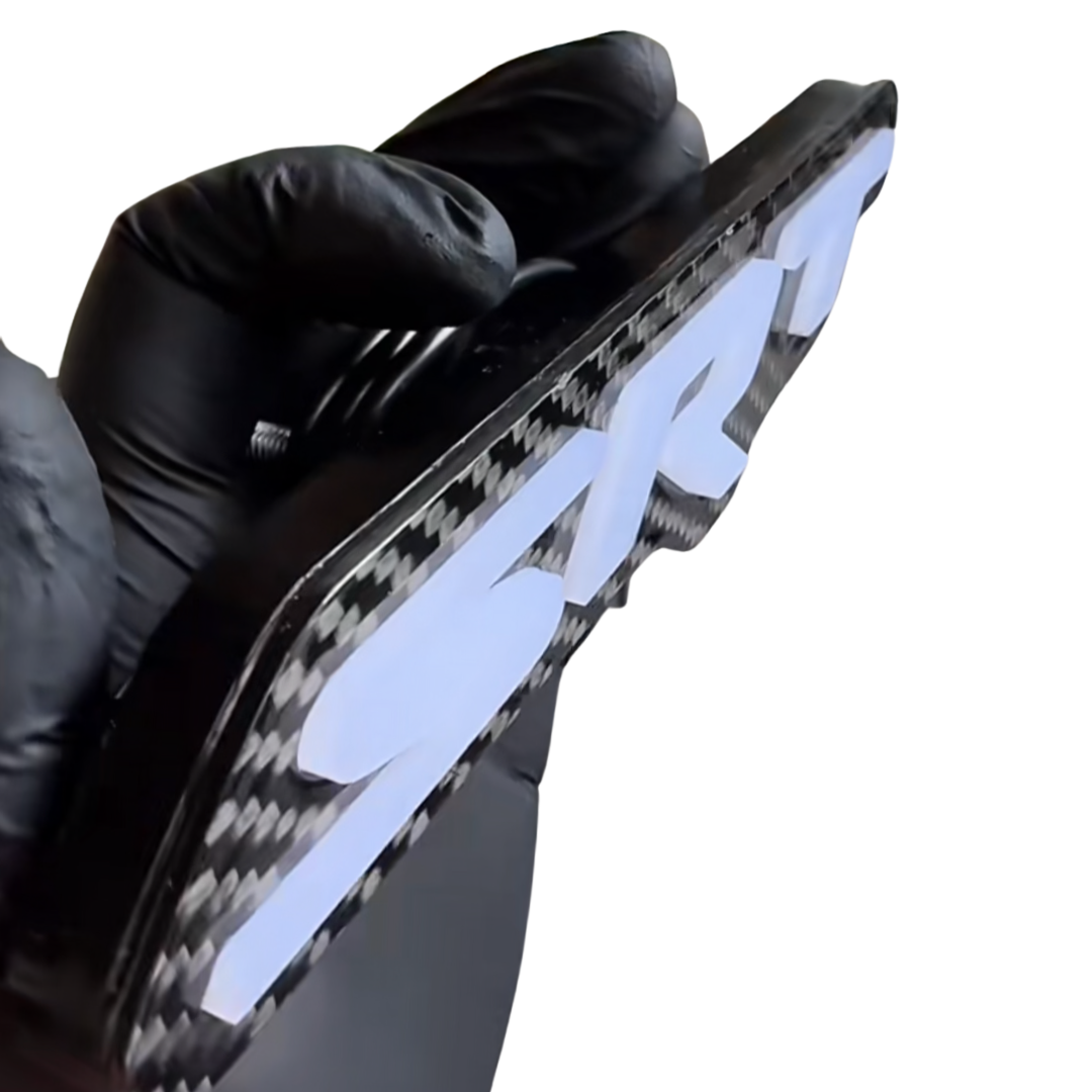 Side-profile close-up of the powered-off carbon fiber SRT LED emblem showing its raised white letters and layered depth.