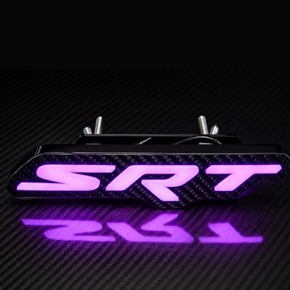 Premium Carbon Fiber SRT RGB LED grille emblem glowing purple with gloss carbon fiber faceplate, raised 3D white lettering, and premium black housing