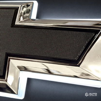 Macro detail of chrome and black Chevrolet bowtie emblem showing textured black center and white LED halo