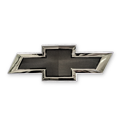 Chrome and black Chevrolet bowtie grille emblem with textured black center and chrome trim, front view on white background