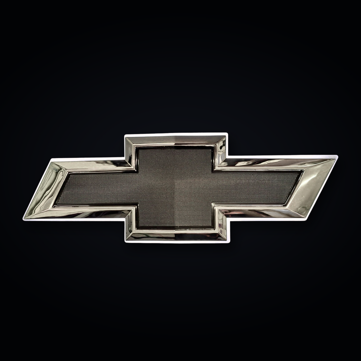 Chrome and black Chevrolet bowtie emblem with OEM-style textured black center on black studio background