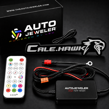 AutoJeweler custom RGB Flow Series badge kit contents with Cale Hawk emblem, RF remote, RGB controller, wiring harness, and branded packaging.