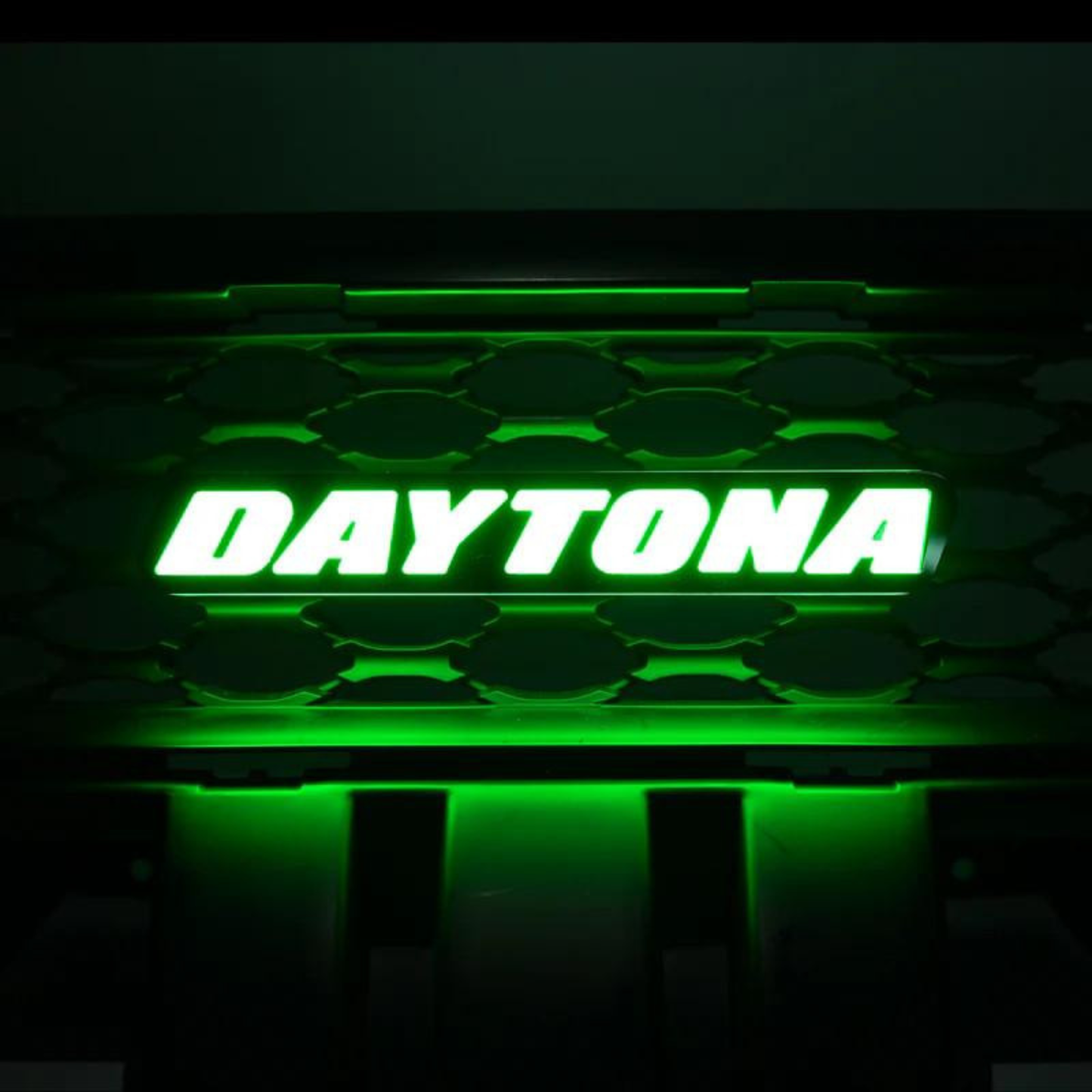 Daytona LED grille emblem illuminated in vivid green lighting mode mounted on black grille background