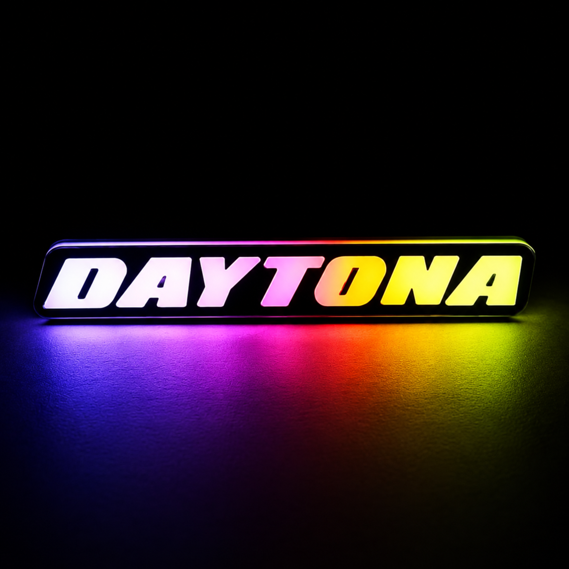 Daytona RGB Flow Series LED grille emblem displaying multicolor rainbow lighting effects on dark studio background