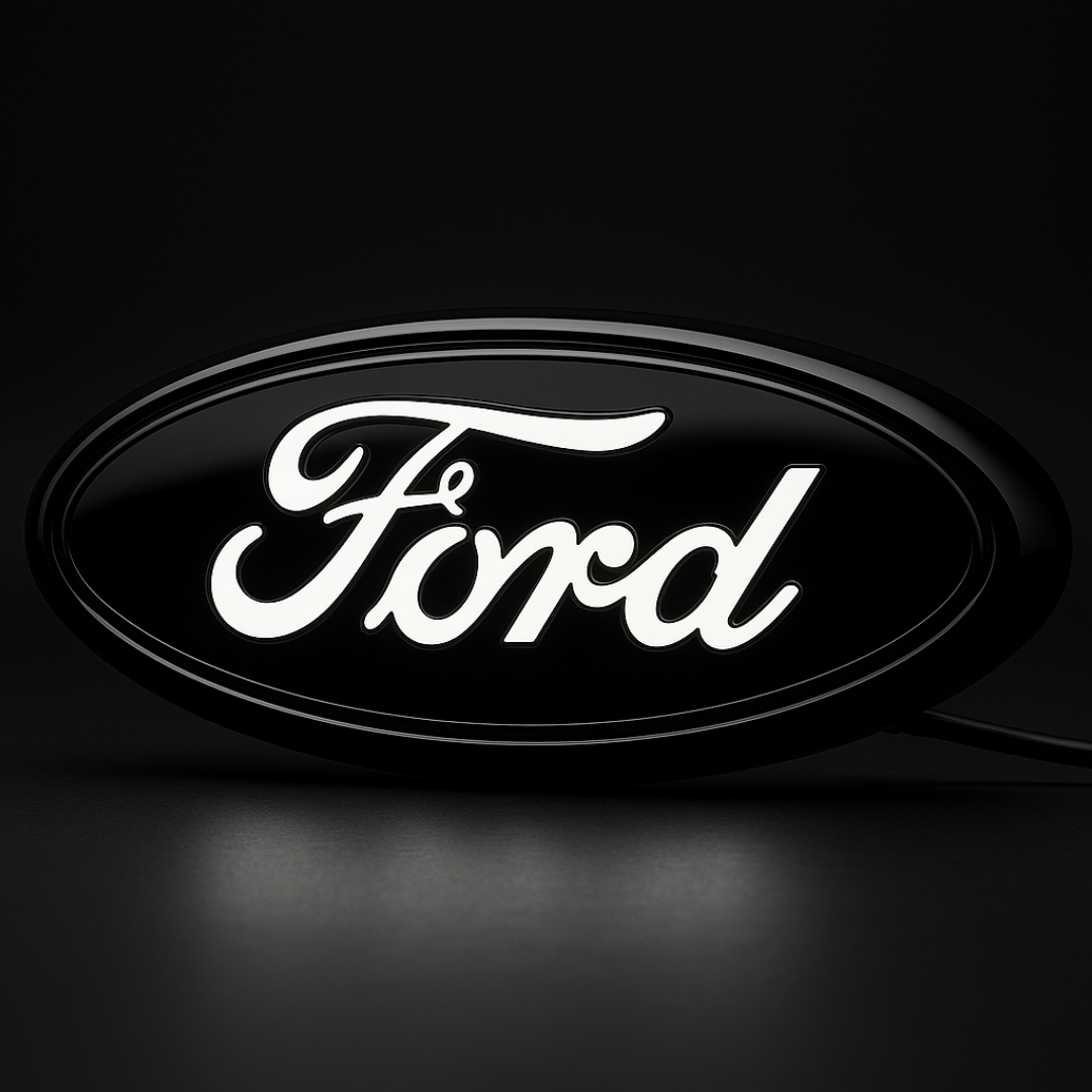 AutoJeweler 9-inch Ford LED grille emblem with letters illuminated white on a dark studio background