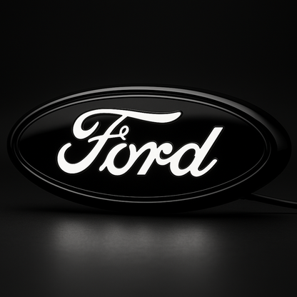 AutoJeweler 9-inch Ford LED grille emblem with letters illuminated white on a dark studio background