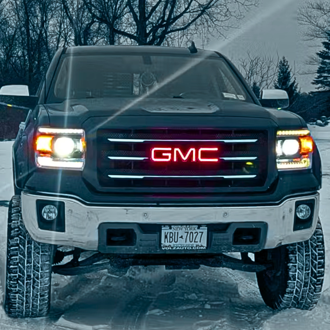GMC truck with red RGBW illuminated grille emblem in snowy driveway