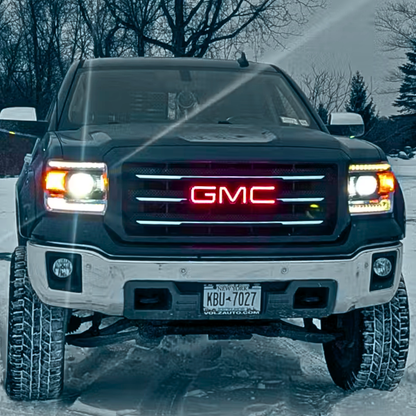 GMC truck with red RGBW illuminated grille emblem in snowy driveway