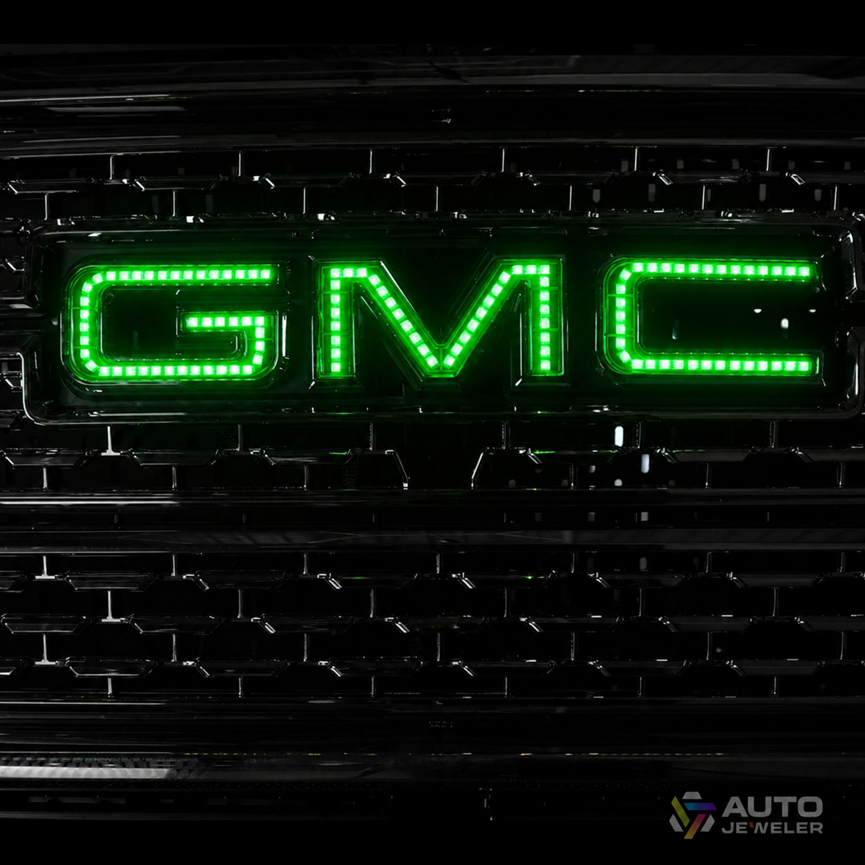 AutoJeweler green RGBW GMC LED illuminated grille logo installed on a GMC Sierra front grille.