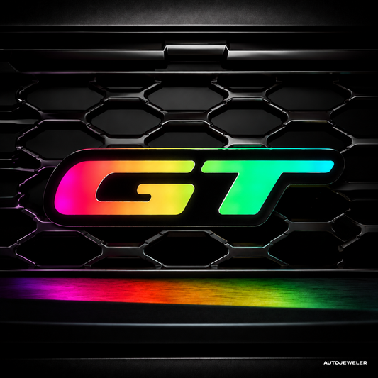 RGB Flow Series GT LED grille badge featuring multicolor chasing illumination on a black honeycomb grille, Bluetooth-controlled custom performance emblem.