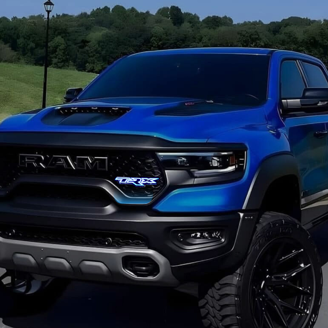 RGB Flow Series TRX LED grille badge installed on the front grille of a blue RAM TRX