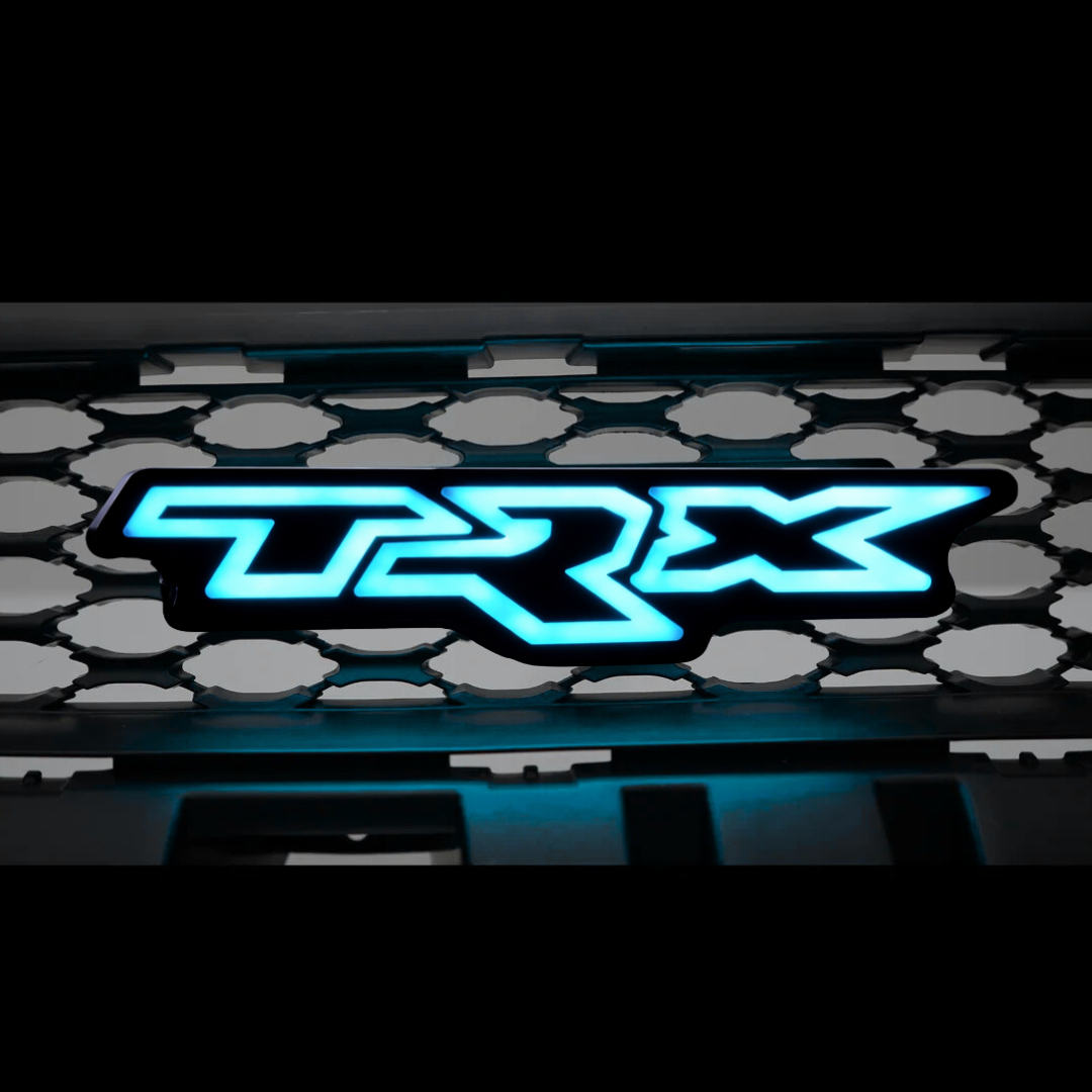 RAM TRX LED grille emblem illuminated in solid blue lighting on black studio background