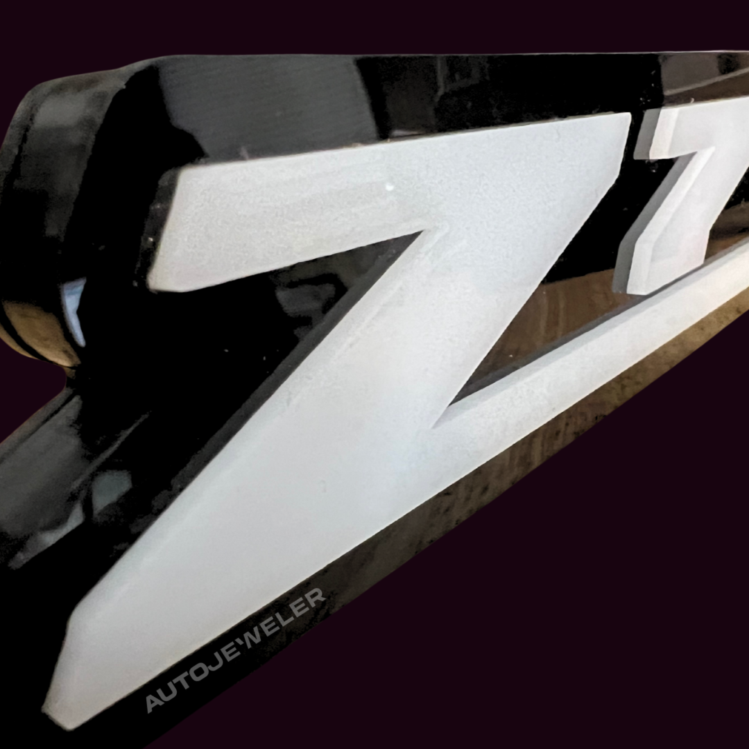 Close up of AutoJeweler Z71 LED grille emblem showing white acrylic lettering and premium black housing construction