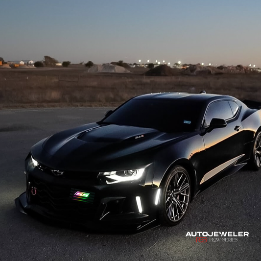 Chevy Camaro SS parked at dusk with RGB Flow Series LED grille emblem installed, multicolor lighting visible on front grille