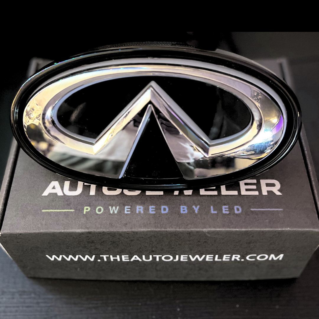 Chrome car emblem on a branded box with 'The Auto Jeweler' branding.