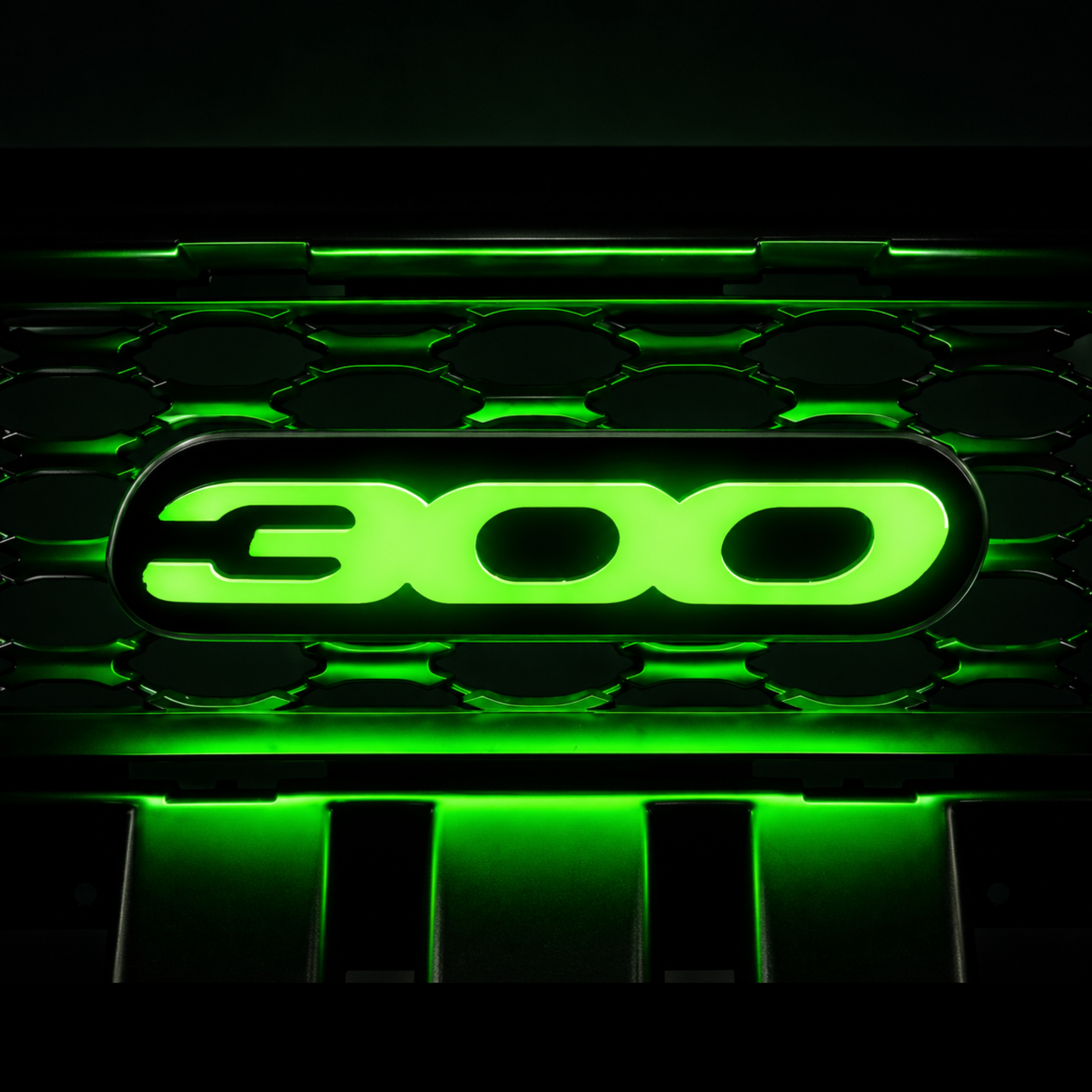 Chrysler 300 illuminated grille emblem glowing bright green with high-output LEDs, gloss black acrylic faceplate, and custom luxury sedan grille installation.