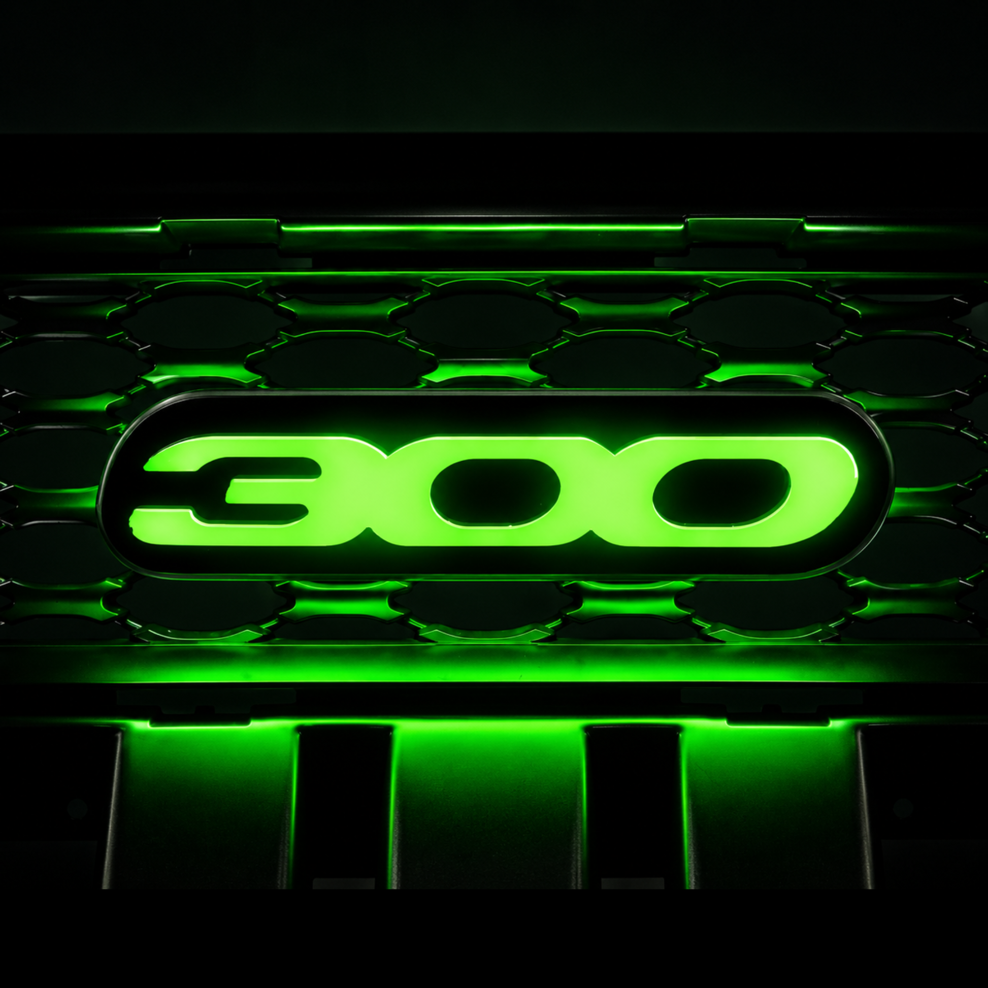 Chrysler 300 illuminated grille emblem glowing bright green with high-output LEDs, gloss black acrylic faceplate, and custom luxury sedan grille installation.