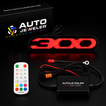 Chrysler 300 LED grille emblem kit illuminated in red featuring RGB Flow Series badge, AutoJeweler controller, RF remote, wiring harness, and premium packaging.