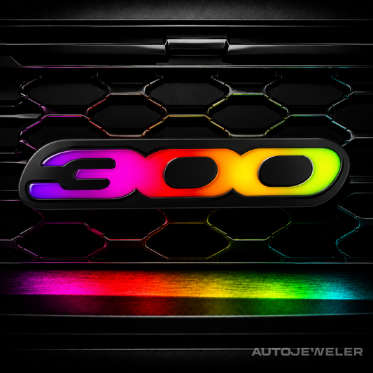 AutoJeweler Chrysler 300 LED grille emblem illuminated in RGB Flow Series rainbow mode featuring animated multicolor lighting, gloss black acrylic housing, and premium illuminated 300 badge design.
