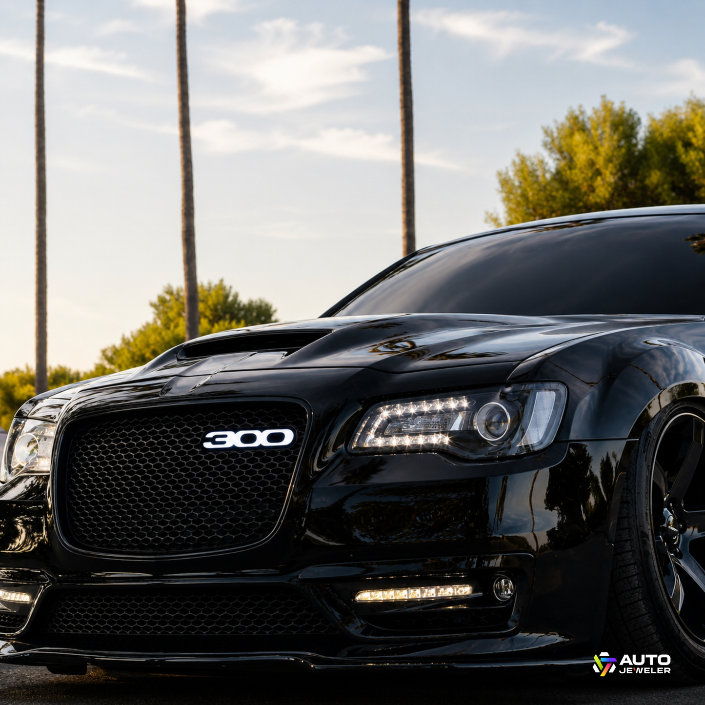 White illuminated Chrysler 300 LED grille emblem installed on a black Chrysler 300 with mesh grille mounting and premium custom appearance.