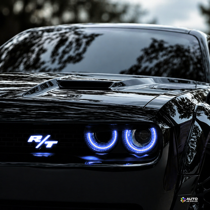 Dodge Challenger R/T front view with blue LED grille emblem and halo headlights illuminated, showcasing custom automotive lighting upgrade by AutoJeweler