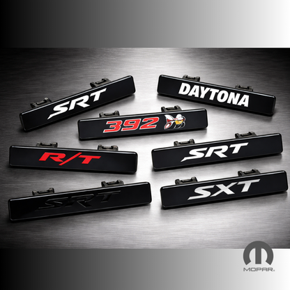 Set of car emblems with 'SRT', 'Daytona', '392', 'R/T', and 'SXT' on a dark surface, featuring Mopar logo.