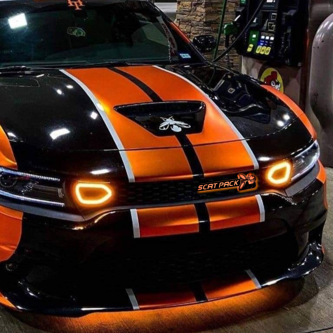 Orange and black dodge srt scatpack  with orange underglow lighting and a scatpack rgb led grille emblem glowing bright orange at Bucee's gas station while parked at the gas pump