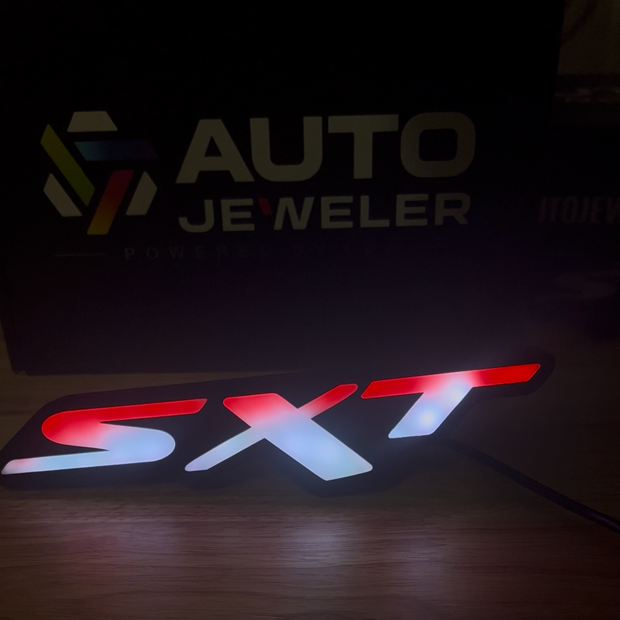 Dodge SXT Flow Series LED grille emblem illuminated in red and white during an AutoJeweler bench test